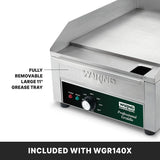 Close-up of a Waring Countertop Electric Griddle, highlighting its fully removable large 11 grease tray. Control knobs and indicator lights are visible. Text at bottom reads: “INCLUDED WITH WGR140X.” Ideal for international use.