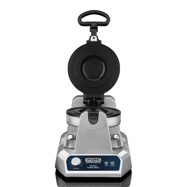 A silver Waring commercial waffle maker with a heavy duty, non-stick cooking surface is open, showing the round black plates. The upright handle and front control panel with indicator lights are visible. The background is white.
