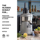 A silver Waring heavy duty Juice Extractor sits on a counter near apples, celery, and a lemon. Text reads: The WJX80X is built for continuous pulp ejection—ideal for producing large quantities of juices in juice bars, restaurants, hospitals, and hotels.