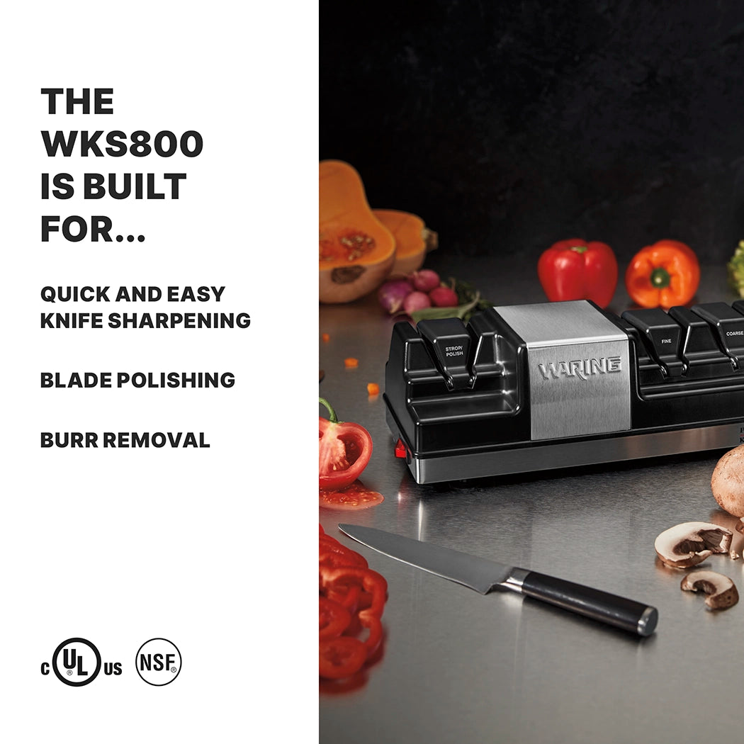 A Waring WKS800 electric knife sharpener sits on a kitchen counter near chopped vegetables and a chef’s knife. Text highlights quick sharpening, blade polishing, burr removal, and the durable grinding wheels. Certification logos line the bottom.
