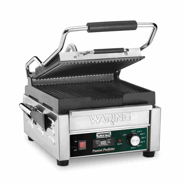 A stainless steel Waring commercial panini grill with ribbed cast iron plates, black handles, side utensil holder, temperature control knob, indicator lights, and an open, angled lid. The front displays branding and controls.