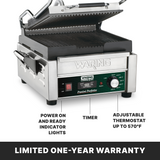 A compact panini grill, this stainless steel Waring Commercial panini press features ribbed cast iron plates, a timer, adjustable thermostat up to 570°F, power/ready indicator lights, and a limited one-year warranty highlighted at the bottom.