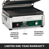 A stainless steel Waring Panini grill with ribbed cast iron plates, indicator lights, a timer dial, and an adjustable thermostat knob up to 570°F. Text below highlights its large cooking surface and limited one-year warranty.