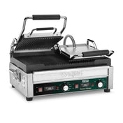 A stainless steel Waring WPG300T dual panini grill with a hinged, ridged top plate lifted open, revealing black grill plates. The front features control knobs, switches, indicator lights, and a green label reading Panini Ottimo.