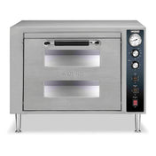 A stainless steel electric pizza oven with a front door featuring two rectangular viewing windows, a black handle, and a right-side control panel with temperature gauge, switches, and indicator lights. The countertop oven stands on four metal legs.