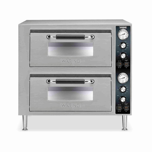 A commercial stainless steel double-deck pizza oven with two pull-down doors, black handles, control knobs, switches, and temperature gauges on the right side panel, all standing on four short metal legs—a perfect countertop pizza oven for any busy kitchen.