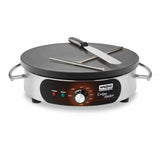 A stainless steel electric crepe maker with a black nonstick cooking surface, temperature dial, power and ready indicator lights, and two side handles. A metal spatula and T-shaped batter spreader rest on this electric crepe maker.