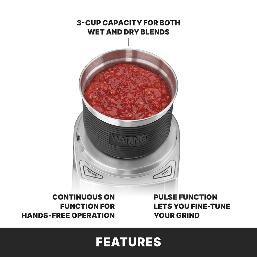 A top view of the Waring WSG60KSDI Commercial Spice Grinder with a metal bowl filled with red tomato sauce. Text highlights its 3-cup capacity for wet and dry blends, continuous hands-free operation, and pulse function for precise grinding.