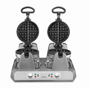 A heavy duty Commercial Belgian Waffle Maker with two round non-stick plates opens vertically, side by side. The metallic base features dual control knobs, indicator lights, and handles for easy use. The modern design suits any professional kitchen.