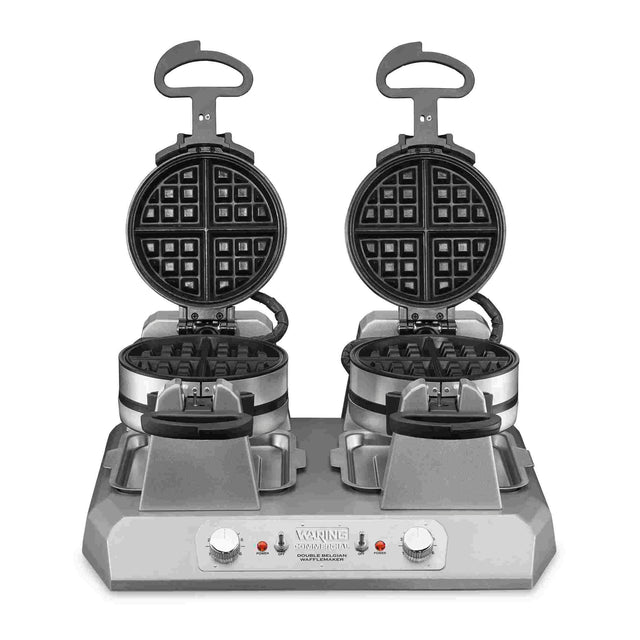A commercial Belgian waffle maker with quad side-by-side round non-stick plates is open, revealing the grids. The sturdy, rectangular “Waring” base has two control knobs, indicator lights, and raised black handles.