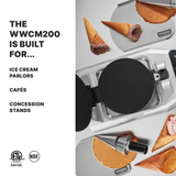 A Double Waffle Cone Maker sits open on a countertop surrounded by finished waffle cones, some dipped in chocolate and sprinkles. Text reads: “The WWCM200 is built for... Ice cream parlors, cafés, concession stands.” Certification logos are below.