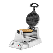 A Classic Waffle Maker with shiny stainless steel and non-stick plates features a round waffle inside. The open lid reveals the grid plates, knob, two indicator lights, drip tray, and a curved black handle for easy use.