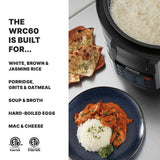 A close-up of a PFAS-free non-stick pot rice cooker filled with cooked white rice sits on a countertop. Nearby, naan bread and a blue plate with rice and curry are visible. A list highlights its multi-cooker uses; certification logos appear below.