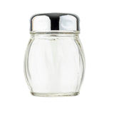 A clear, empty glass cheese shaker with subtle vertical grooves stands upright. It has a round, shiny metal lid with small holes for dispensing salt. The plain white background highlights the TableCraft cheese shaker’s simple, reflective design.