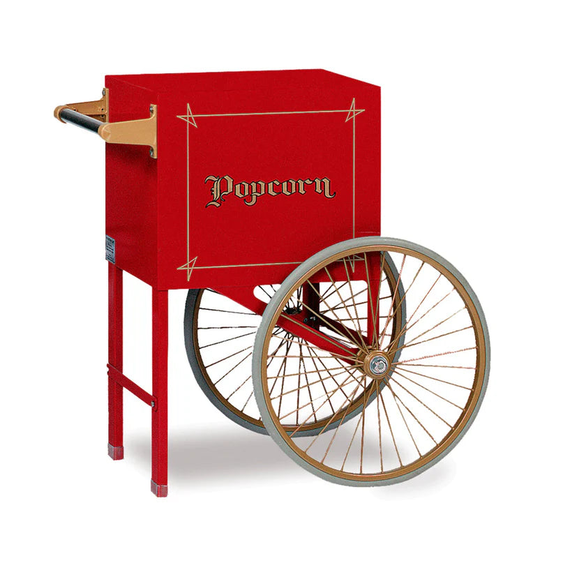 A vintage-style red popcorn cart with gold accents by Gold Medal Products, featuring two large spoked wheels, a rectangular box labeled “Popcorn” in ornate script, front legs for stability, and wooden handles on the back for easy pushing.