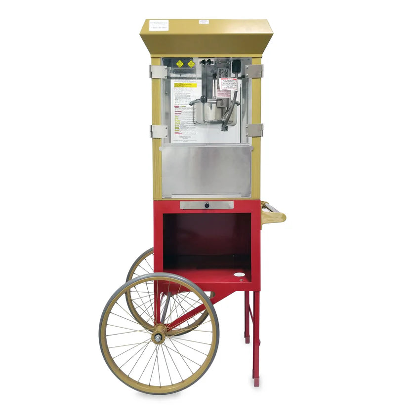 A vintage-style popcorn machine with a gold top, clear glass sides, and a red base on a cart with large gold wheels and a wooden handle. This antique deluxe popcorn maker features visible popper and posted instructions inside the enclosure.