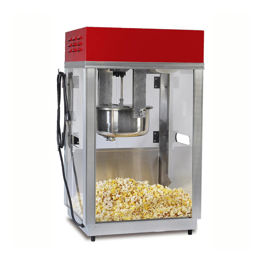A commercial Popcorn Machine with a red top, glass sides, and metal base sits on the countertop. Inside, a 6 oz kettle pops fresh popcorn, with the pot and stirring mechanism visible. Ventilation slots are on the front and side panels.