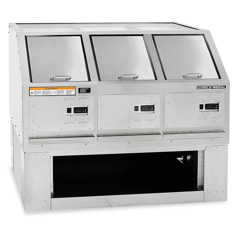 A commercial stainless steel utensil washer with three tilted, insulated compartments and digital controls. Features warning labels, an open storage shelf below for popcorn storage, and a reflective surface. The unit is branded “Gold Medal.”.