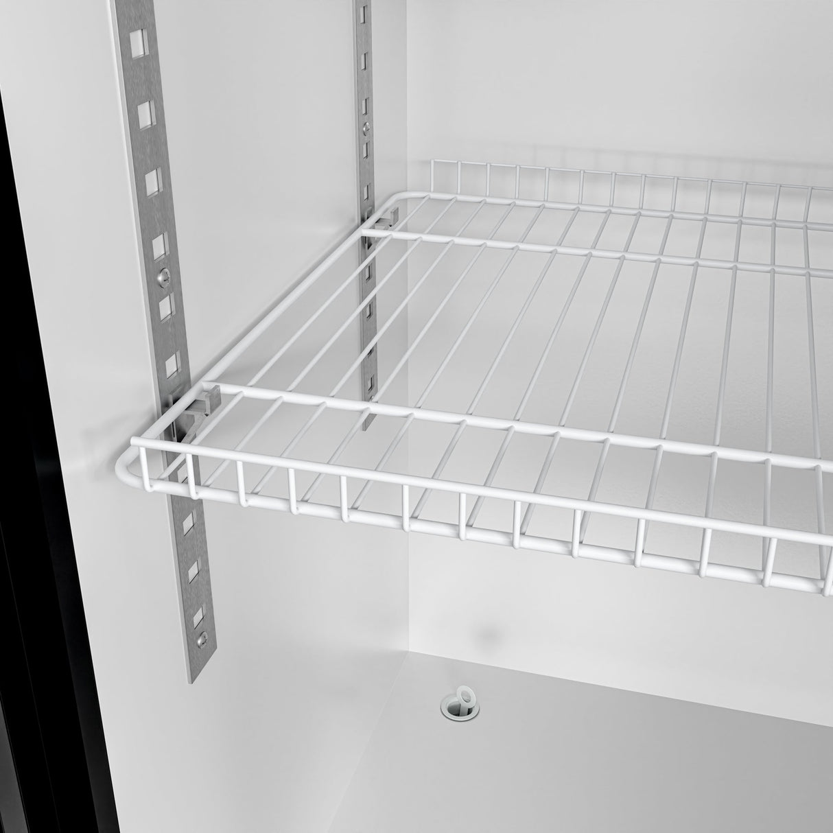 Close-up of a metal wire shelf inside a white cabinet, similar to shelving found in a commercial merchandiser refrigerator. The shelf is supported by metal brackets on vertical tracks, with the cabinet bottom and a small round fixture visible below.