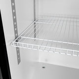 Close-up of a metal wire shelf inside a white cabinet, similar to shelving found in a commercial merchandiser refrigerator. The shelf is supported by metal brackets on vertical tracks, with the cabinet bottom and a small round fixture visible below.
