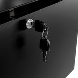 A close-up of a black metal drawer with a key in a silver lock, reminiscent of the sleek design found in a slim refrigerator. Another identical key hangs beside it, both against a background of smooth, shiny black metal.