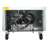 The image shows the underside of a commercial refrigerator on four wheels. A black power cable is coiled and secured to a metal mesh panel, revealing interior wiring and mechanical parts. The floor is white and the background is plain.