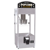 A self-serve popcorn popper with a silver metal frame, clear glass sides, a metal kettle inside, and a dispenser chute at the bottom. This countertop model features a top sign reading “Self Serve POPCORN HOT & FRESH” with popcorn graphics.