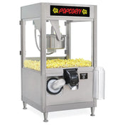 A stainless steel ReadyPop Popcorn Popper filled with yellow popcorn. It features a transparent glass case, a “POPCORN” sign on top, a self-serve dispenser at the front, and a holder with clear plastic bags on the side.