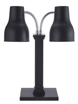 A modern, minimalistic black Double Heat Lamp features two adjustable necks extending from a central rectangular stem on a flat base. Each bell-shaped lamp head is angled outward to provide versatile lighting options.