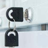 A close-up of a black key inserted into a silver lock on a white surface, often found on commercial display refrigerators. Another key is attached to the same keyring. The keys and lock are in sharp focus, with Hettich and XIH visible on the keys.