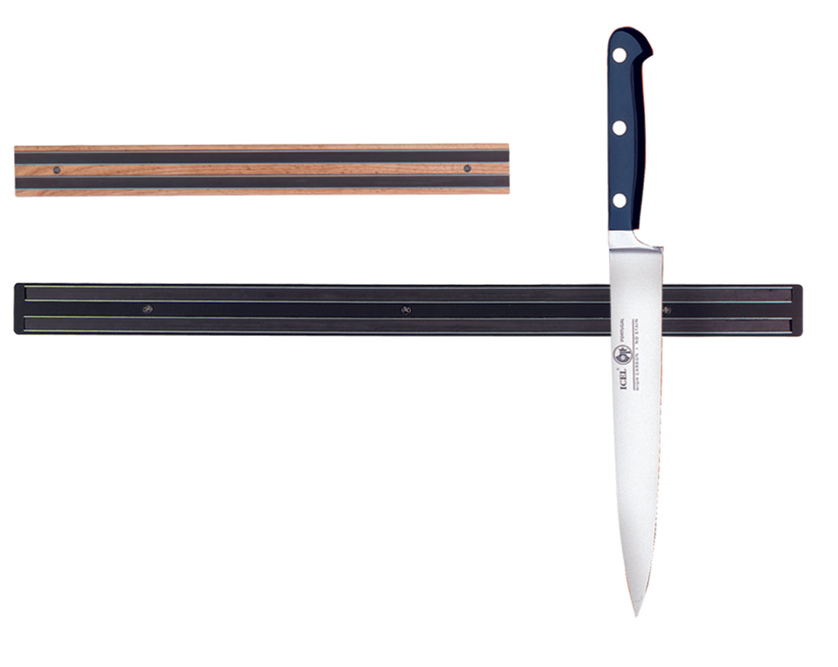 A magnetic holder is mounted on a white wall. One wood strip is empty above, while the lower wall mount secures a large chef’s knife with a black handle and three rivets held horizontally by the magnet.