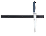 A long kitchen knife with a black handle is attached vertically to an 18 inch magnetic holder mounted on a white wall. The strip, typical of Cash & Carry displays, holds only the single knife, and the blade is shiny and pointed downward.