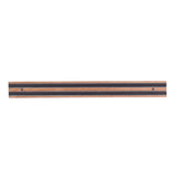 A wooden magnetic holder with alternating light and dark wood stripes, mounted horizontally on the wall. Two screws secure this smooth, flat wall mount, which is designed to hold metal kitchen tools securely in place.