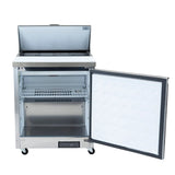 An Empura Refrigeration stainless steel Salad Prep Table is shown with its top lid open and door wide. Inside, there’s a wire shelf and empty compartment. The plain white interior of the front door contrasts with the fridge’s black wheels.