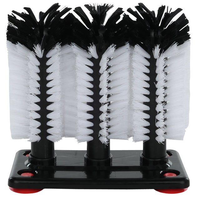 A close-up of a triple glass washing brush—part of a professional-grade bar glassware cleaning system—with four vertical cylindrical brushes, three with white bristles and one black, on a black base with red suction cups at the corners.