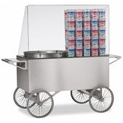 A stainless steel cotton candy cart with four large spoked wheels, a clear display case, and stacks of pink and blue cotton candy bags inside. The cart has handles on both ends for pushing and a round spinning machine for making cotton candy.