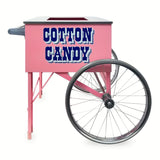 A Pink Floss Cart with large metal wheels and bold blue letters on the side that read COTTON CANDY. Made by Gold Medal Products, this floss unit cart has an open top, a left handle, and a charming vintage carnival feel.