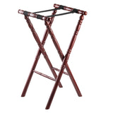 A polished wooden luggage rack with carved spindle legs in an X-shape and a rich mahogany finish. Two wide, slip-proof black fabric straps span the top for holding suitcases. The rack stands on a white background.