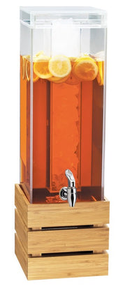A tall, clear 3 gallon beverage dispenser filled with iced tea and lemon slices stands on a wooden base. The BPA Free dispenser features a central ice core and a silver spigot at the front for easy pouring.