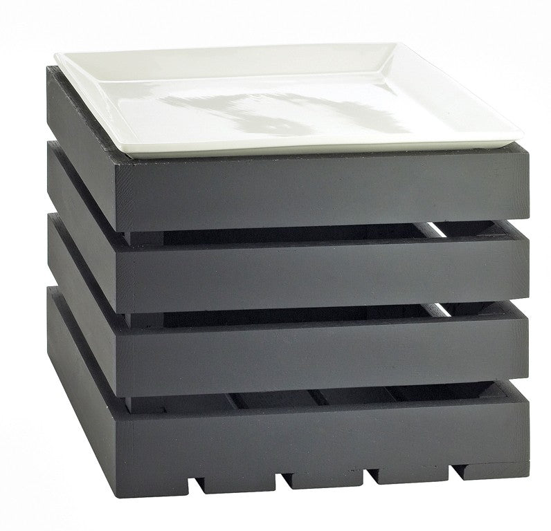A white, square ceramic plate sits atop the modern Midnight Bamboo Crate Riser—a black, slatted shelf riser with four stacked layers and evenly spaced gaps, resembling a display basket with a solid base.