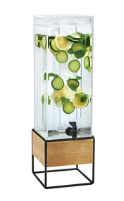 A tall, clear 3 gallon beverage dispenser filled with water, ice, lemon slices, cucumber slices, and mint leaves stands on a black metal and wood base accented by rustic pine panels. A black spigot is at the front for easy dispensing against a plain white background.
