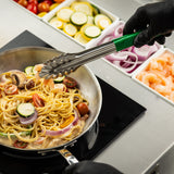 A chef wearing black gloves uses 12 inch tongs to add shrimp to a skillet of creamy pasta with cherry tomatoes, zucchini, mushrooms, and red onion. Containers of sliced vegetables and shrimp sit on the prep counter; the tongs are dishwasher safe.
