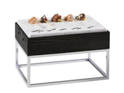 A modern Cinderwood Display Riser with a black wooden base and chrome legs, topped with a white faux marble melamine tray labeled with names of cheeses. Five small cheese samples on toothpicks are arranged in a row on the BPA Free slab.