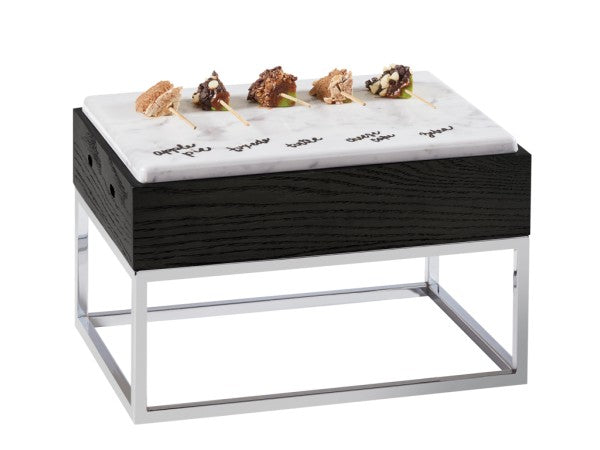A modern Cinderwood Display Riser with a black wooden base and chrome legs, topped with a white faux marble melamine tray labeled with names of cheeses. Five small cheese samples on toothpicks are arranged in a row on the BPA Free slab.