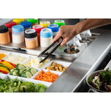 A hand uses stainless steel tongs to pick up sliced boiled eggs from a salad bar filled with fresh vegetables and toppings. Behind the bar, various bottles of salad dressings are organized by color. A bowl of mixed greens sits in the corner.