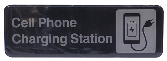 A rectangular Cash & Carry Sign reads Cell Phone Charging Station in large white letters on a black background. To the right, there's an icon of a smartphone with a charging symbol and a plugged-in power cord.