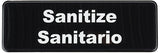 A rectangular black bilingual sign with the word Sanitize on the top line and Sanitario below, both centered in white text. This Sanitize sign is ideal for marking dishwasher safe areas.