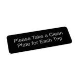 A black rectangular clean plate sign from TableCraft Products with white text reads, Please Take a Clean Plate for Each Trip. The self adhesive backing makes it easy to mount. Photographed at a slight angle against a white background.