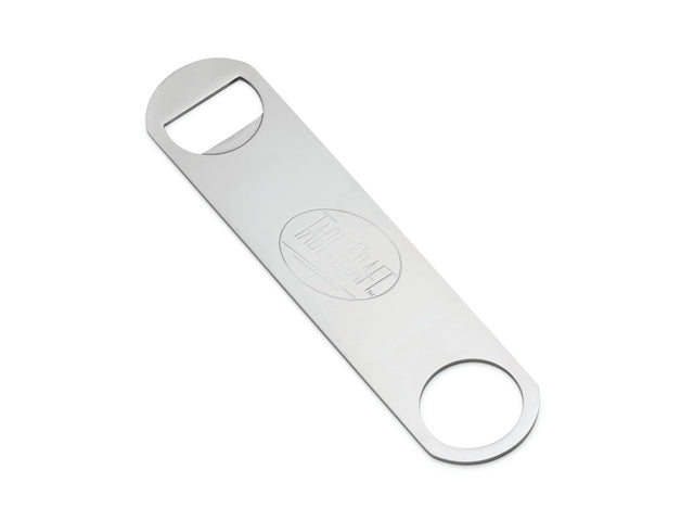 A stainless steel pocket bottle opener with a brushed finish, featuring a rectangular body and rounded ends. One end has a standard bottle-opening notch, the other a large hole. TEAM CRAFT is engraved in the center and it’s dishwasher safe.