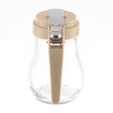 A clear teardrop glass syrup dispenser with a beige plastic lid and handle. The lid features a silver metal flap with a hinged spring mechanism for pouring. This dispenser is dishwasher safe and photographed against a white background.